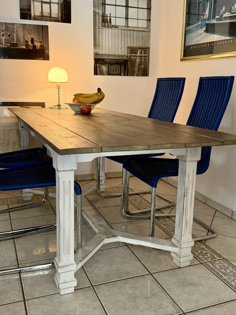 Alter Esstisch aus dem Möbel-Bahnhof im Esszimmer. Der restaurierte Holztisch mit weißem Untergestell war viele Jahre Teil des Eventbahnhofs und dient heute als Esstisch.