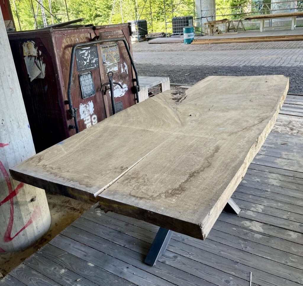 Eine Bohle, zwei Tische: Unbehandeltes Brett aus Schwarzpappel unter der Brücke auf dem Gelände des Möbel-Bahnhofs vor der Weiterverarbeitung.