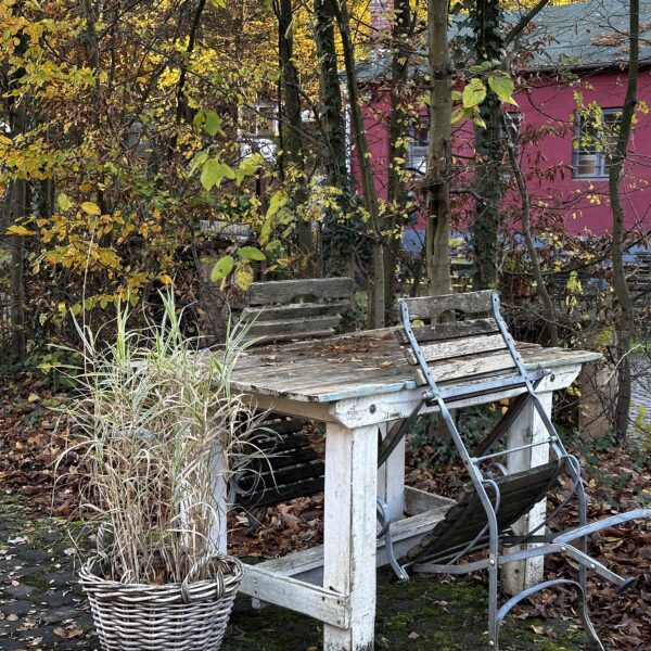 Gemütlich wohnen im Herbst: alter Holztisch und Stühle im herbstlichen Möbel-Bahnhof Bielefeld
